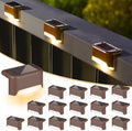 Solar deck lights mounted on outdoor stair risers glowing warm white at night