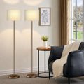 Modern 60 inch floor lamp with white drum shade and foot pedal switch beside a living room sofa