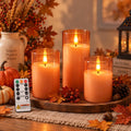 Flameless candles in grey glass holders flickering on a mantel as seasonal decor