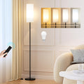 Modern 64 inch floor lamp with rattan shade glowing beside a sofa in a living room