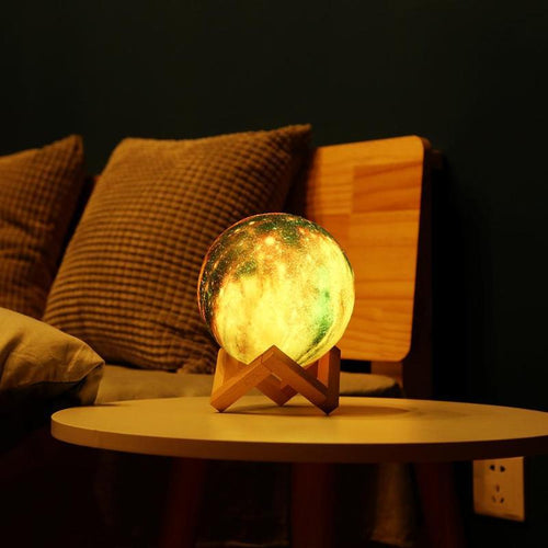 Galaxy-print moon lamp glowing amber on a round table beside a sofa