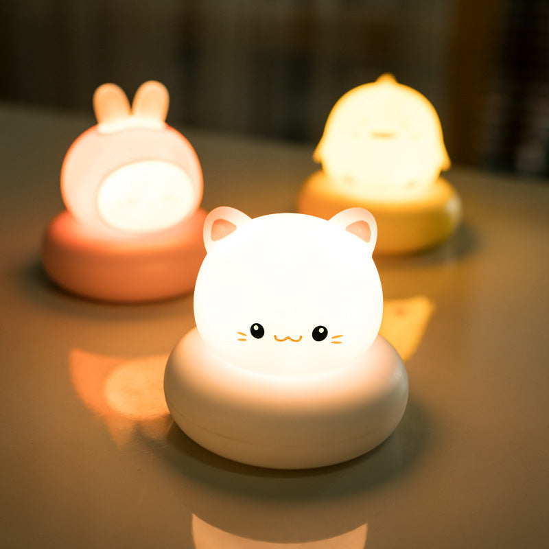 Three silicone animal night lights lit warm on a table: bunny, kitten and duckling