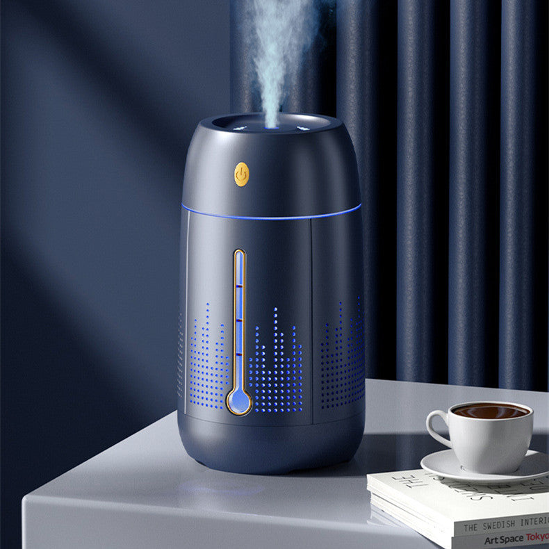 Navy blue aroma humidifier releasing mist on a table beside a coffee cup