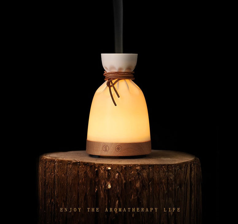 Cream sack-shaped wooden diffuser lit on a tree stump against a dark background