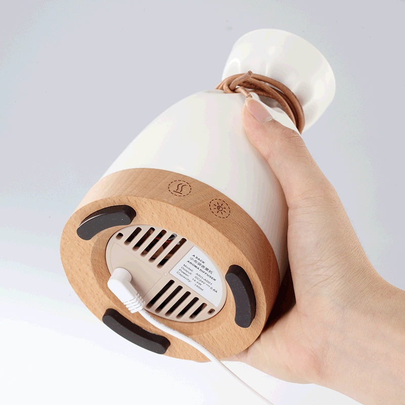 Hand tilting the diffuser to show the vents and switch on its wooden base