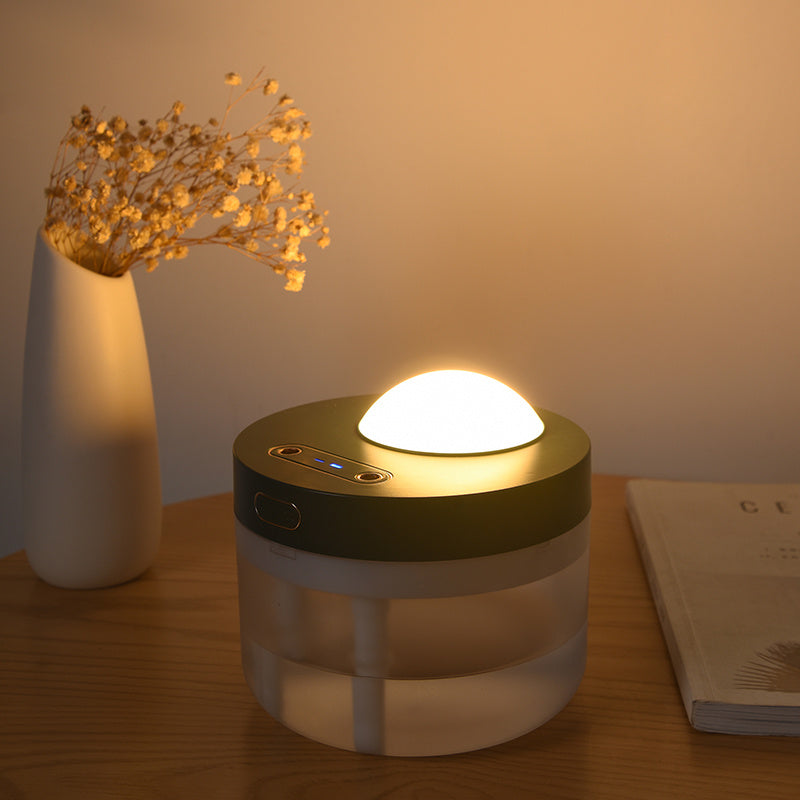 Rotating aroma humidifier lit warm on a desk beside a vase of dried flowers