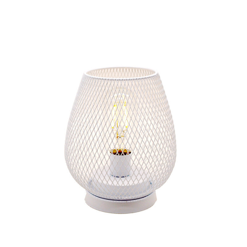 White wire mesh birdcage table lamp with a filament bulb, plain background