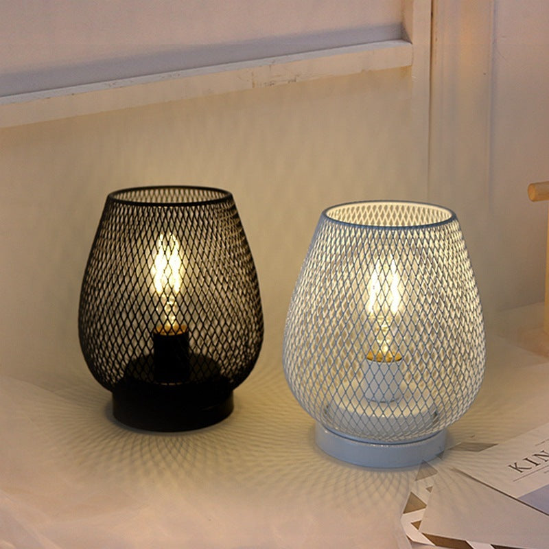 Black and white wire mesh birdcage lamps lit side by side on a windowsill