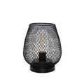 Black wire mesh birdcage table lamp with a filament bulb, plain background
