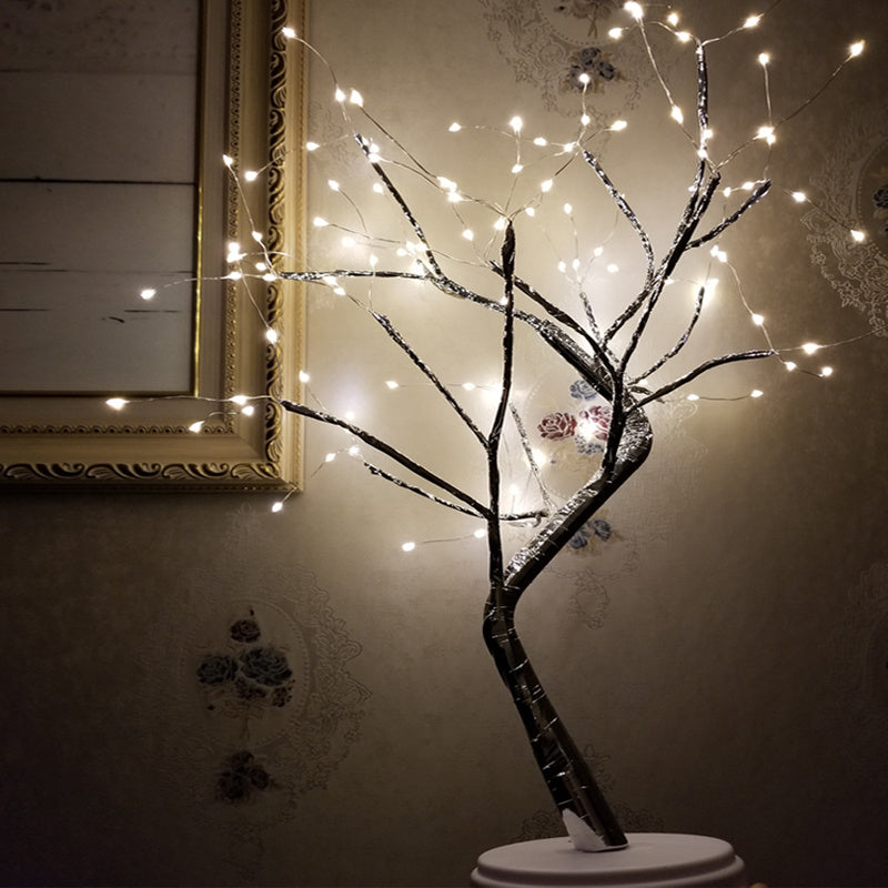 LED bonsai branch tree light lit beside a framed mirror in a dark room