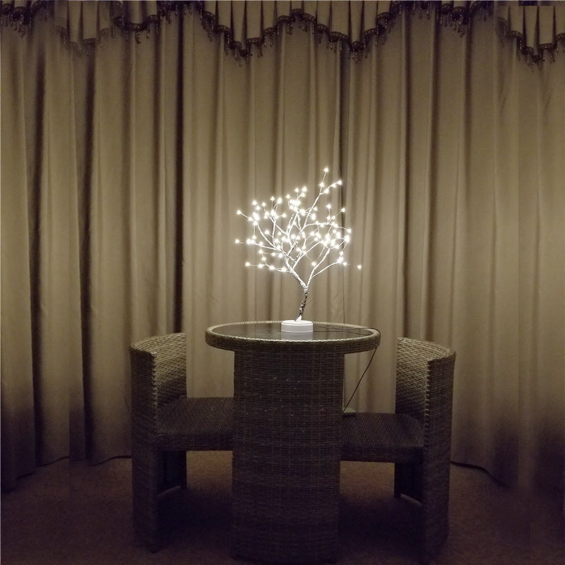 LED bonsai branch tree light glowing on a table in an unlit room
