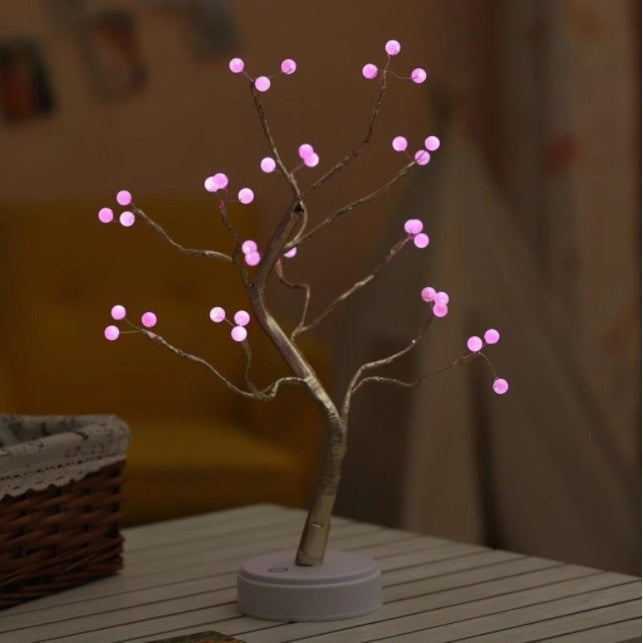 LED bonsai branch tree light with pink bulb tips on a bedside table