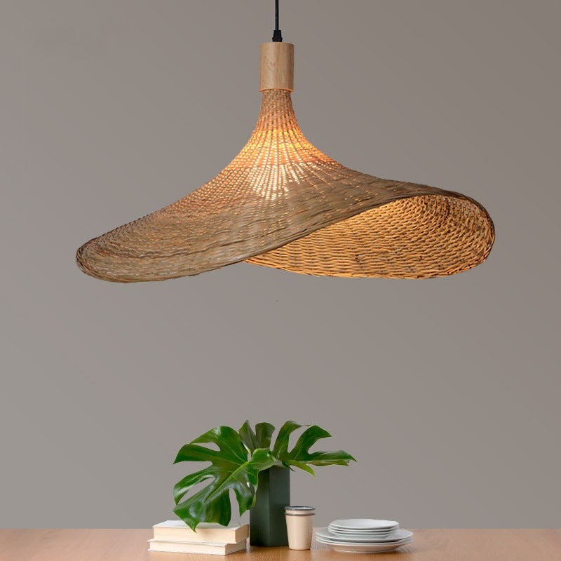 Woven bamboo pendant shade hanging above a shelf with a plant