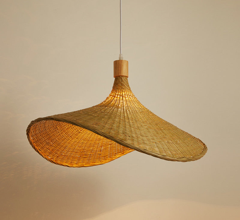 Wide woven bamboo pendant lit warm, showing the folded brim