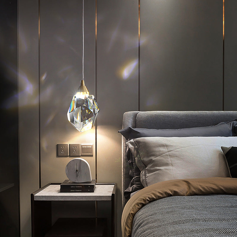 Single crystal pendant light hanging beside a bed, casting light patterns on the wall