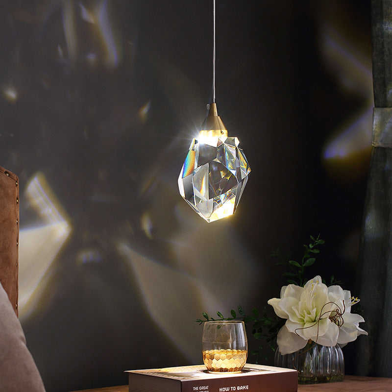 Crystal pendant lit above a side table, scattering light across the wall