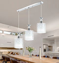 Three cylinder pendant lights on a rail above a dining table