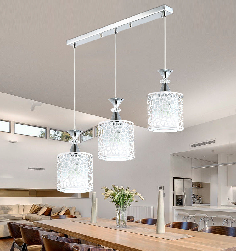 Three cylinder pendant lights on a rail above a dining table