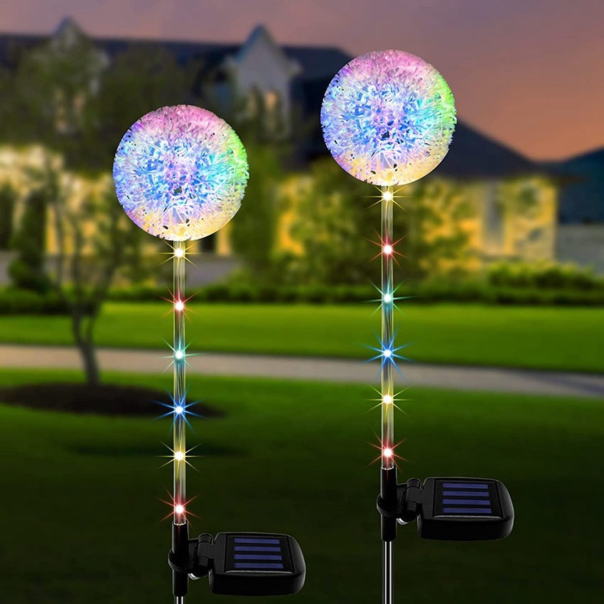 Two dandelion solar lights on a lawn at dusk, solar panels visible on the stakes