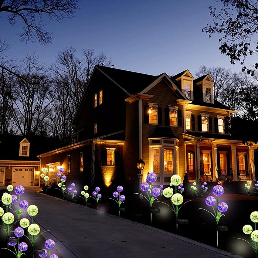 A driveway lined with dandelion solar lights at night in front of a house