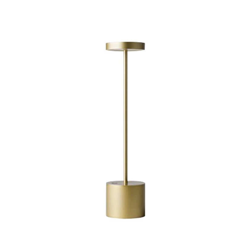 Gold cordless aluminium table lamp seen from the side, plain background