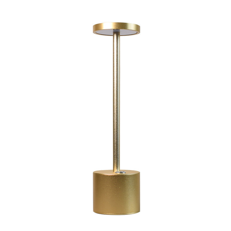 Gold cordless aluminium table lamp lit, plain background