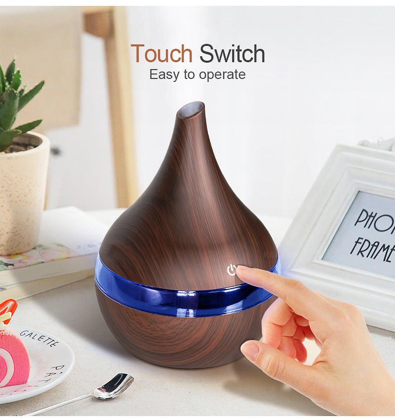 Hand pressing the touch switch on the dark wood-grain diffuser