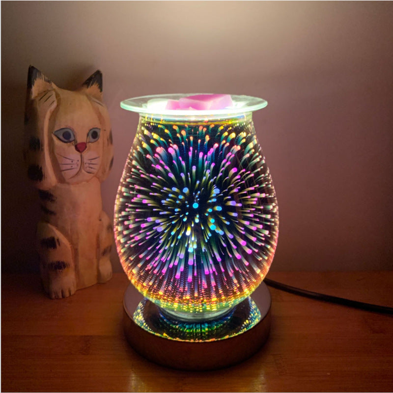 Glass firework aroma lamp lit in multicolour on a wooden base beside a cat figurine