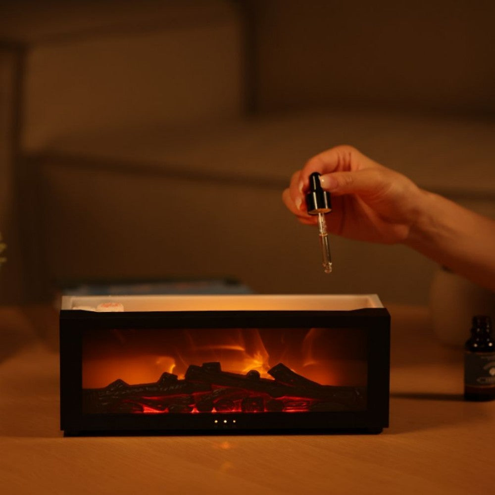 Hand adding oil drops into the top of the fireplace aroma diffuser