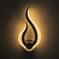 Flame-shaped LED wall sconce lit on a dark wall, warm light spreading upward