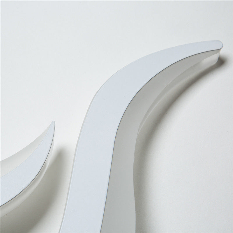 The two white acrylic flame pieces of the wall sconce, unlit