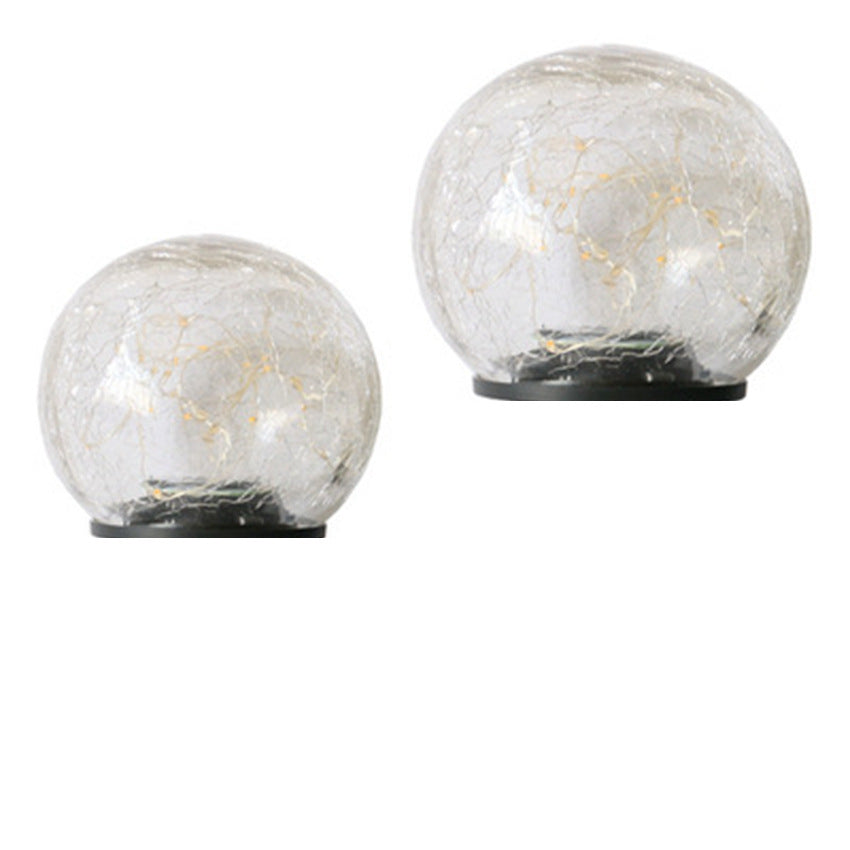 Two crackle-glass solar ball lights, one lit, on a plain background