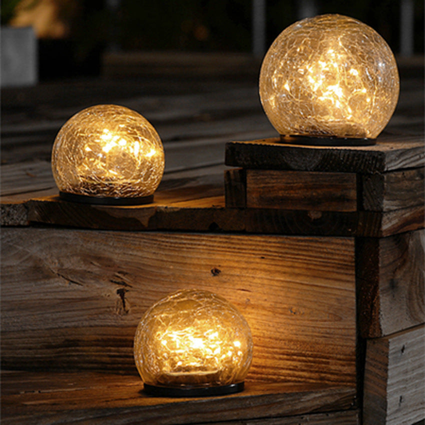 Crackle-glass solar ball lights glowing warm on wooden garden steps