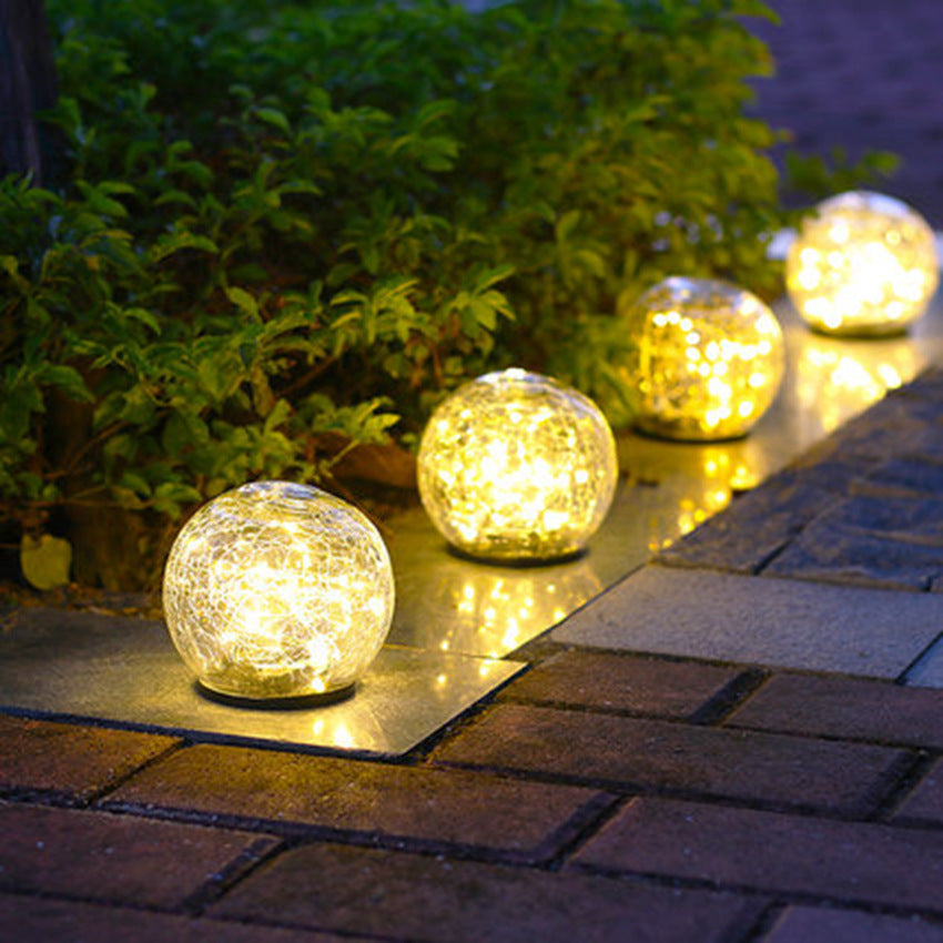 Four crackle-glass solar ball lights lining a garden path at night