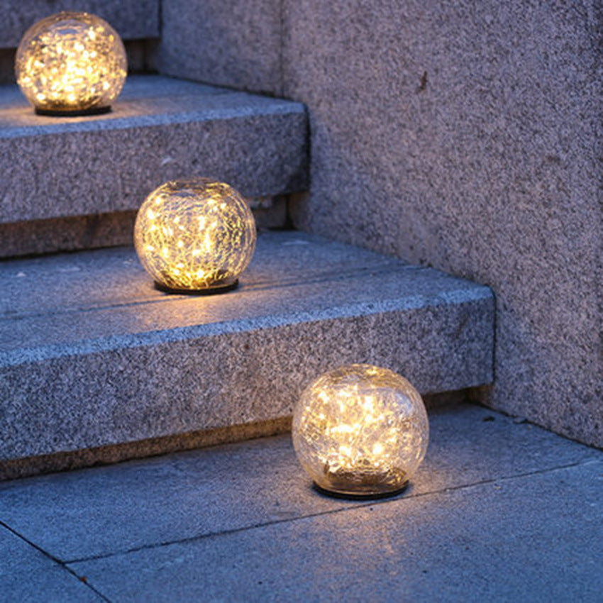 Three crackle-glass solar ball lights glowing on stone steps