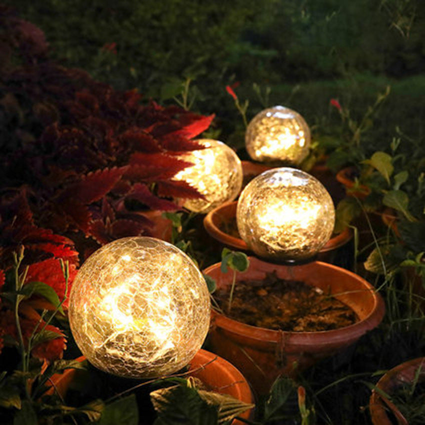 Crackle-glass solar ball lights among autumn foliage and a plant pot