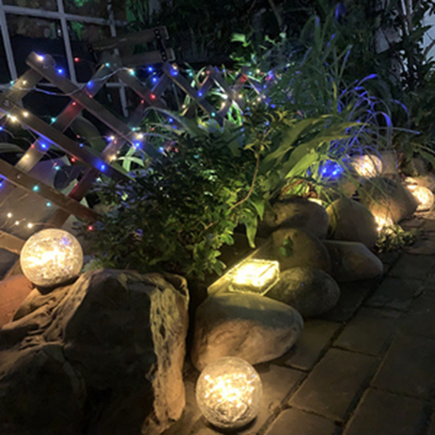 Crackle-glass solar ball light glowing beside a garden border at night