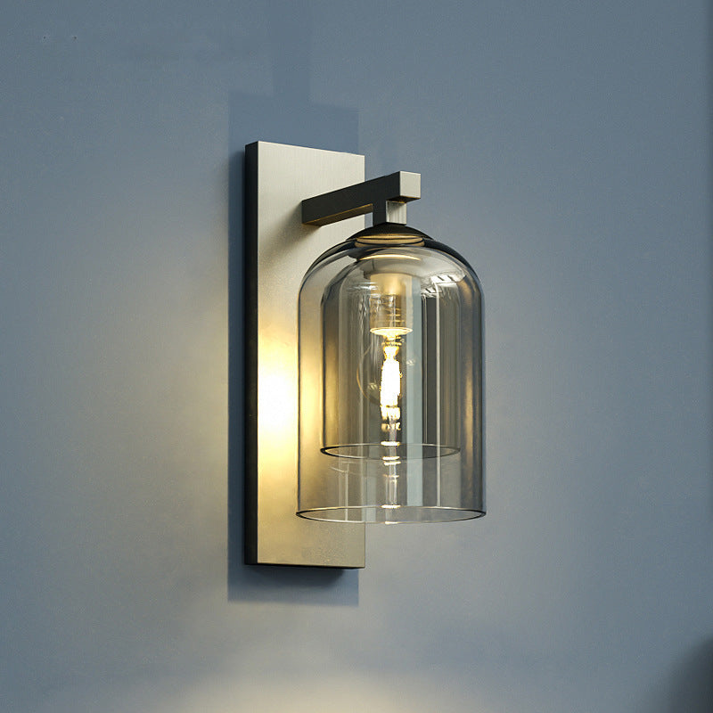 Smoke glass wall sconce lit on a blue-grey wall