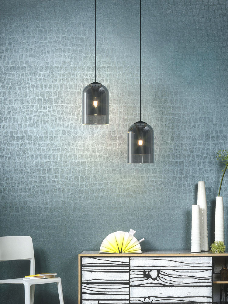 Two smoke glass pendant lights hanging above a sideboard