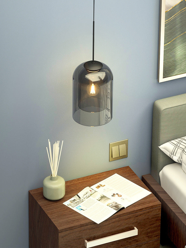 Smoke glass pendant light hanging above a wooden bedside table