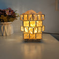 Himalayan salt crystal lamp lit warm on a desk beside a vase of flowers