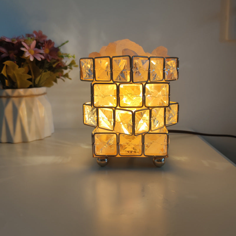 Himalayan salt crystal lamp lit warm on a desk beside a vase of flowers