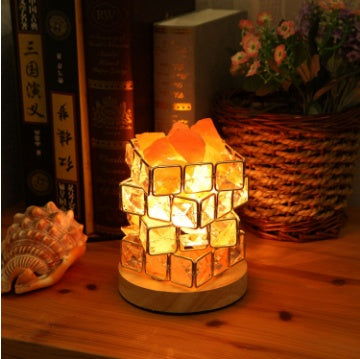 Salt crystal lamp glowing on a wooden table in front of a row of books
