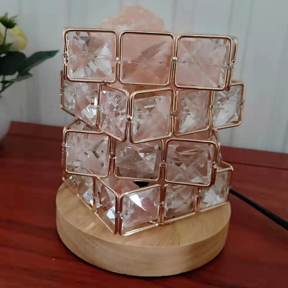 Clear crystal cube lamp on a wooden base, unlit, plain background