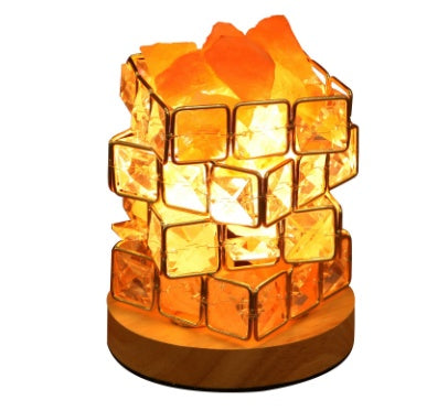 Himalayan salt crystal lamp lit warm on a wooden base, plain background