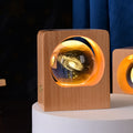 Crystal ball with a galaxy engraving lit amber inside a square wooden frame