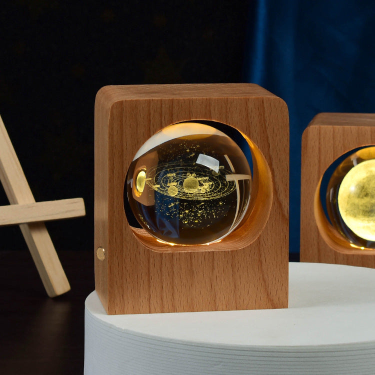 Crystal ball with a solar system engraving lit inside a square wooden frame