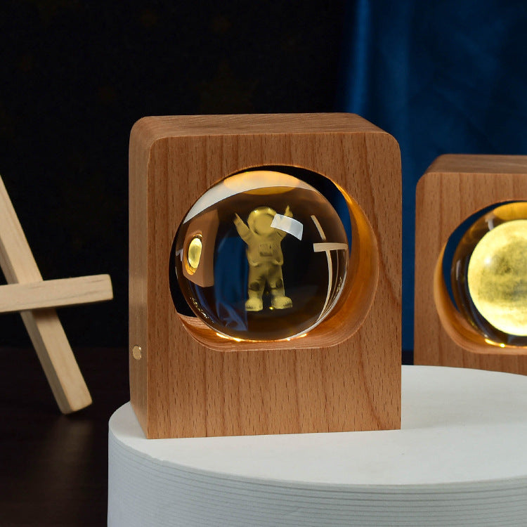 Crystal ball with an astronaut engraving lit inside a square wooden frame