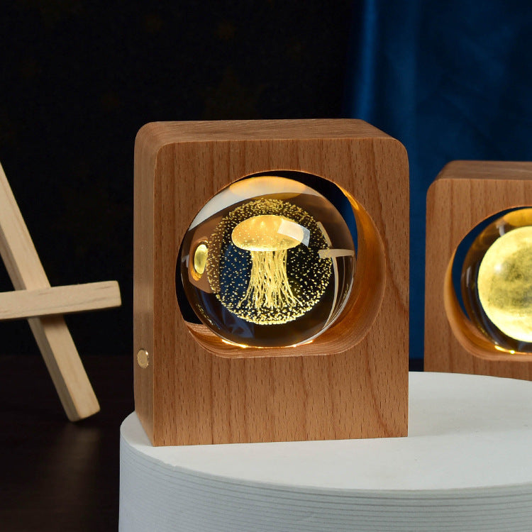 Crystal ball with a jellyfish engraving lit inside a square wooden frame