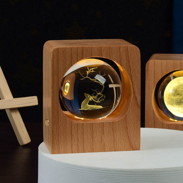 Crystal ball with a deer engraving lit inside a square wooden frame